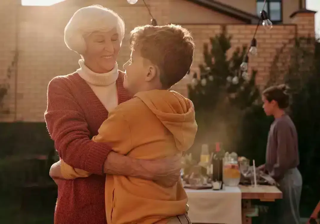 An elderly woman hugging a child 