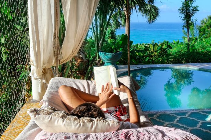 a person lying down reading a book by a pool in antigua and barbuda