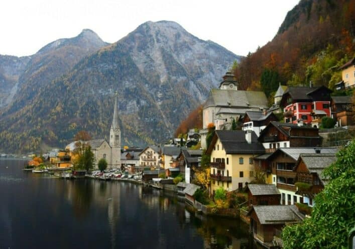 Quaint houses in the Austrian Alps on a misty day with a church tower in the distance - passport by investment