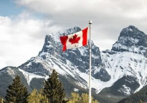 Canadian flag against a snowy mountain backdrop - Golden Visa opportunities worldwide
