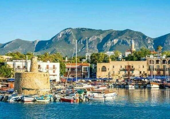 View of Kyrenia harbor in Cyprus with boats moored and a mountain in the background - Cyprus Golden Visa