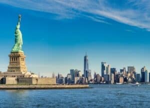 statue of liberty near water with city landscape
