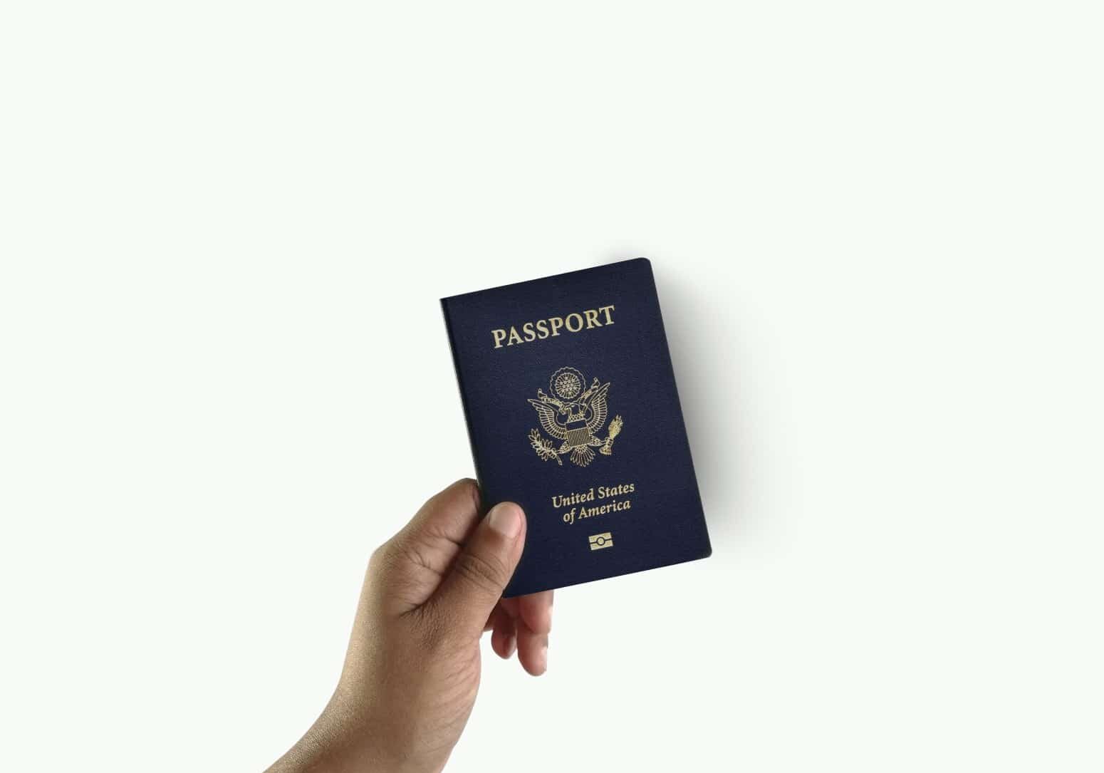 Hand holding up US passport against a white background - getting naturalized as a citizen