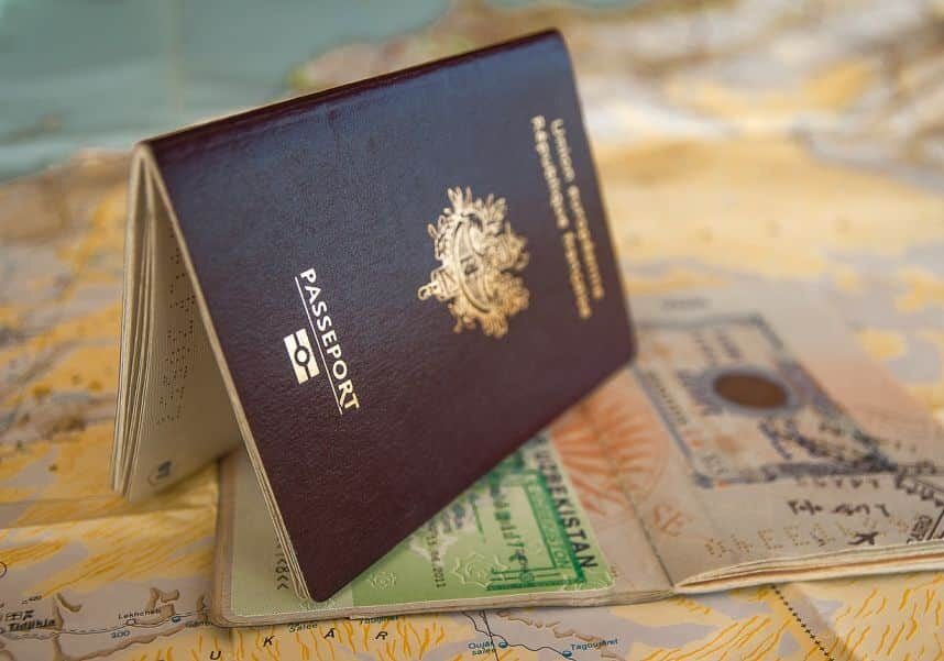 Black passport laying on its side on top of a map - What is a Citizenship by Investment program?