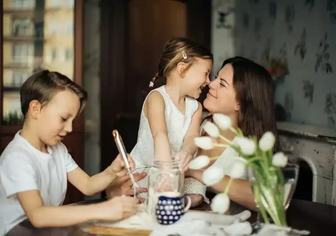 A woman with two children sitting at a table and smiling
