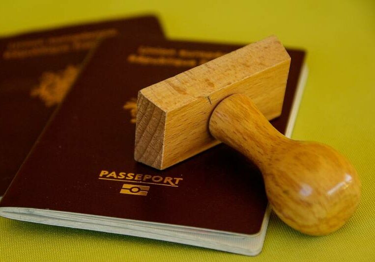 Two passports with a wooden stamp on top of them. 