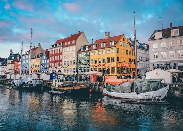 Colorful houses flanking boats moored on a river in Copenhagen, Denmark - country that's safest in Europe
