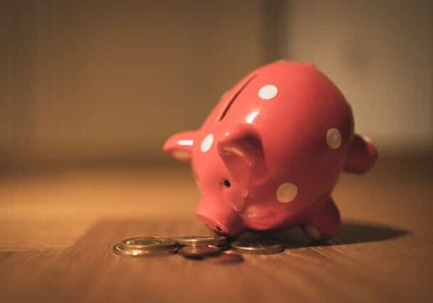 Pink piggy bank standing up on its nose digging in coins on a desk - All Countries that Allow Dual Nationality