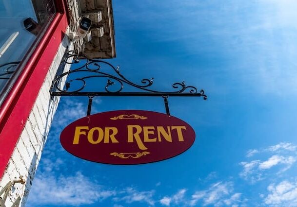 For rent sign hanging on a building with a blue sky