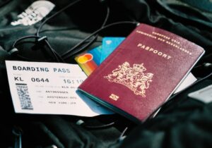 Red passport, boarding pass, credit cards and cords on black travel bag - how to obtain multiple passports