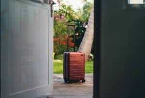 Looking through an open front door at a red suitcase standing on a porch - how to move out of the United States