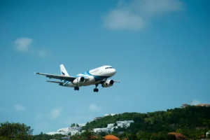 plane in a blue sky landing on a caribbean island
