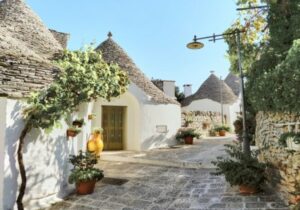 White round houses that look like huts, with a brick walkway and trees around them.