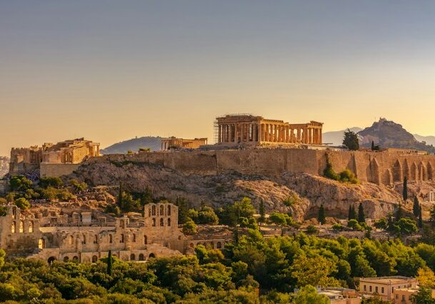 A monument in Greece on a hill surrounded by trees. 