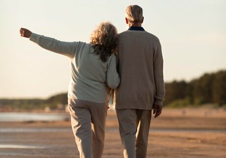 two retired people walking in a beach in spain