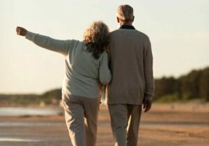 Retired couple walking hand in hand on a beach in Turkey