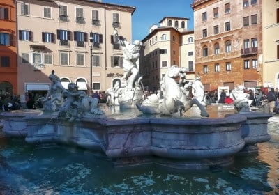 A grand fountain with statues surrounded by buildings in the Lazio. Italy.