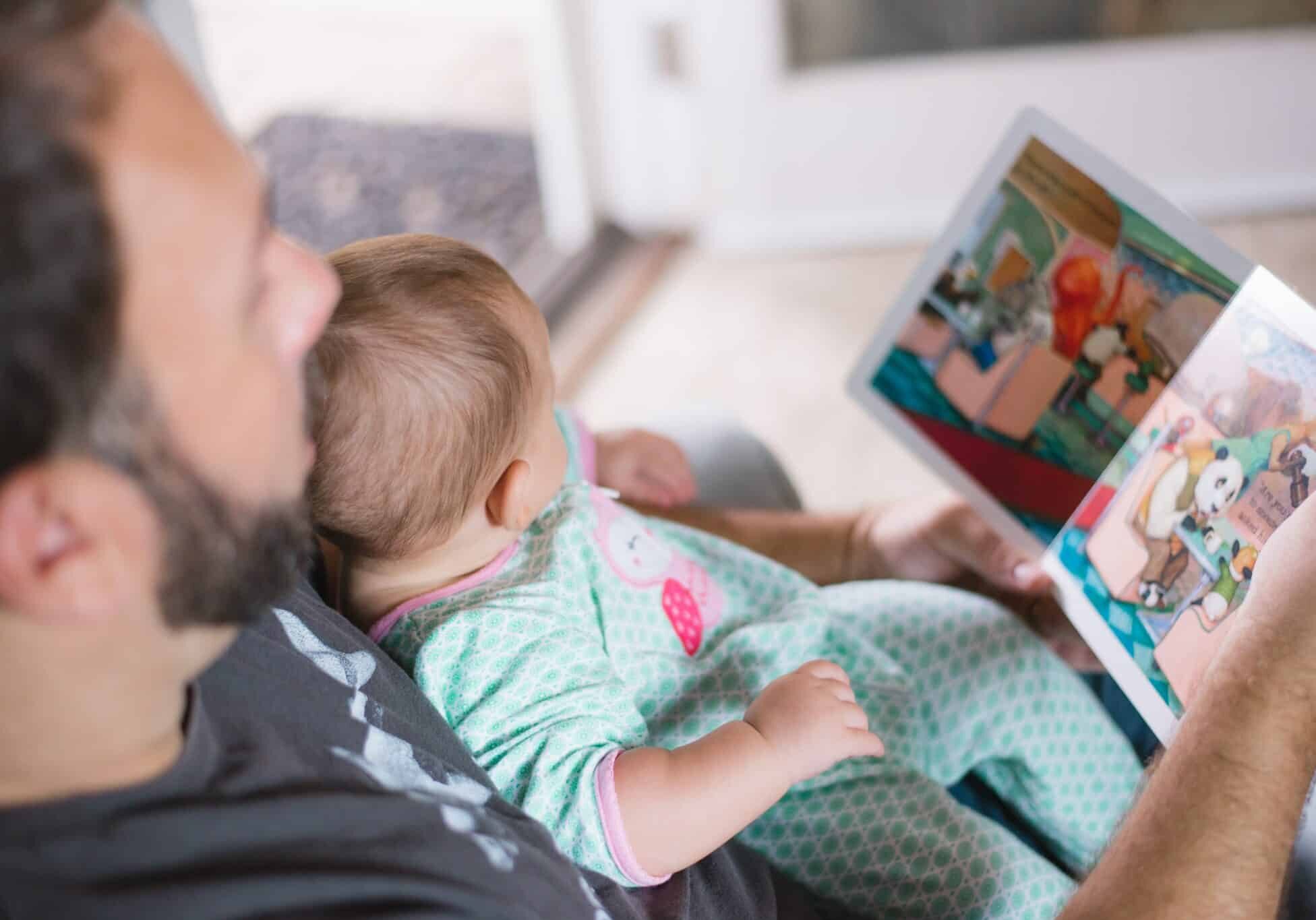 Man reading to a baby sitting in his lap - citizenship by descent - pros and cons of dual nationality