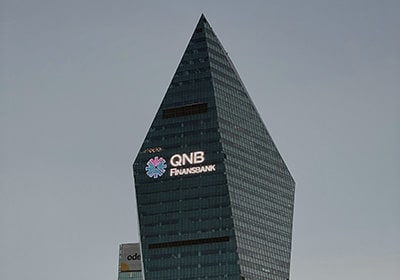 QNB bank logo on a tall office building against a gray sky - best Middle Eastern bank