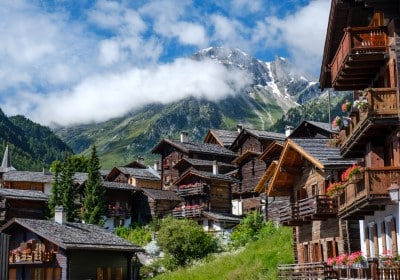 Green mountains with brown houses and a blue sky in Davos, Switzerland.
