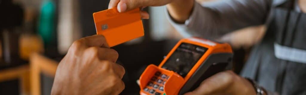 a person with a credit card paying for a meal with a card maching inside a caribbean restaurant