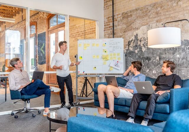people sitting on a sofa discussing plans on a board