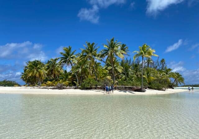 People standing on the beach in the Cook Islands with palm trees in the background - Cook Islands no property tax