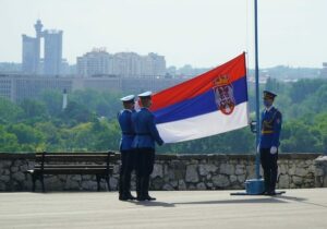 Soldiers holding a Serbian flag with the capital city's skyscrapers in the background - Serbian residency by investment