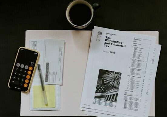 Flat lay image of phone with calculator app laying next to printed out tax documents - requirements for a residence permit