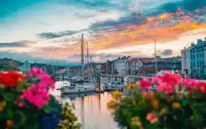 View of Douglas, the charming capital of the Isle of Man during a orangey-yellow sunset with boats moored - no capital gains tax country