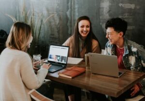 Three people sitting in front of laptops talking at a desk - digital nomad countries