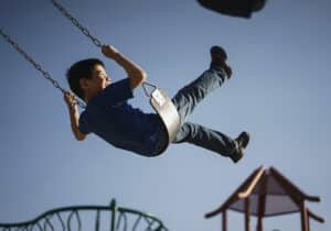 boy playing in a swing on a playground in Latvia