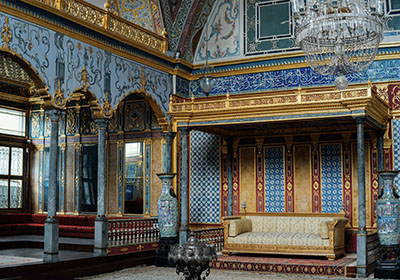 Ornate interior of the Topkapi Palace in Istanbul featuring Ottoman architecture with intricate tilework, gold detailing, arched columns, and a grand chandelier