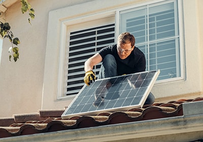 Man on a roof installing solar panels - save on rental property taxes