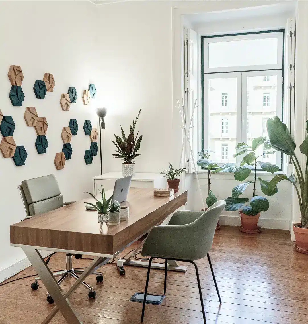 A cozy home office featuring a desk, chair, and several green plants for a refreshing atmosphere.