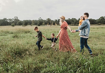 A family of five waling in field with green grass. 
