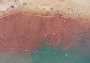 Top view of a beach in Paraguay with visitors swimming in the teal and brown water - safest South American countries