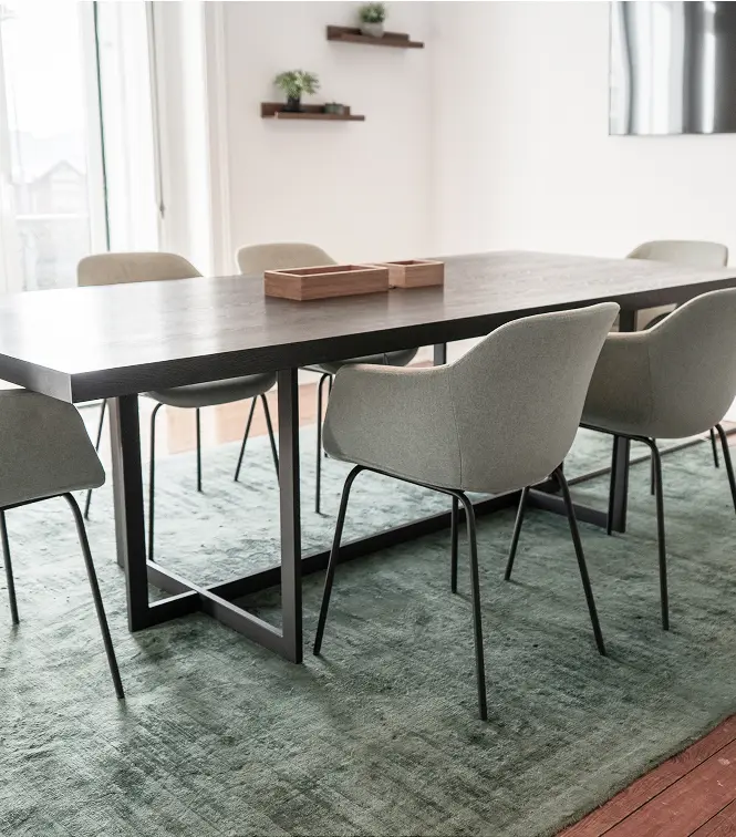A black dining table surrounded by chairs, set for a meal in a well-lit dining area.