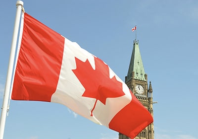 Canadian flag waving in front of the Parliament Building on Parliament Hill in Ottawa