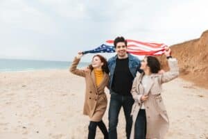 people on a beach holding a flag after getting EB-5 Visa for Indians