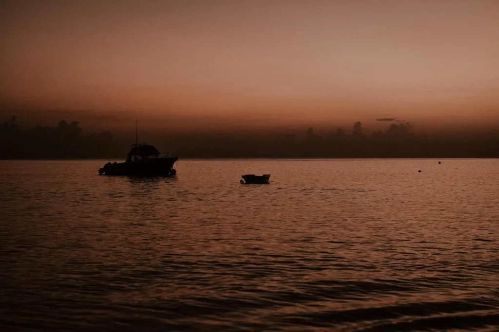 Um pequeno barco flutuando suavemente em águas calmas, sob um céu azul e límpido.