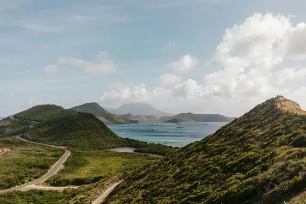 Uma vista panorâmica do oceano e das montanhas a partir de uma colina, revelando águas de um azul vibrante e picos de um verde exuberante.