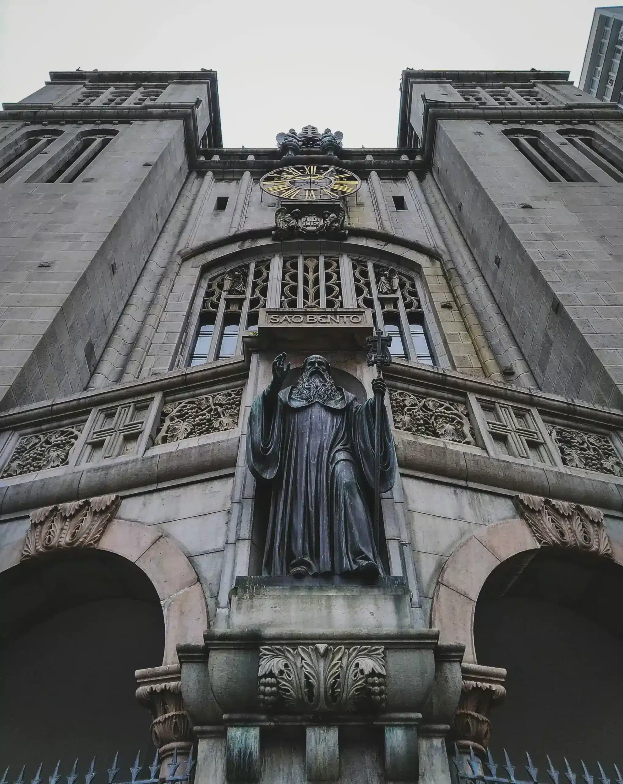 A statue of a man stands atop a building, overlooking the city skyline.
