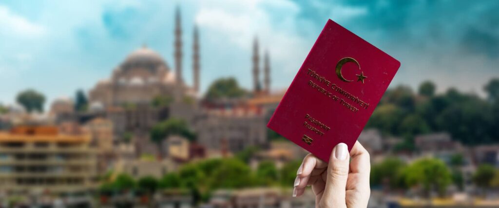 person holding up a Turkish passport in front of a mosque 
