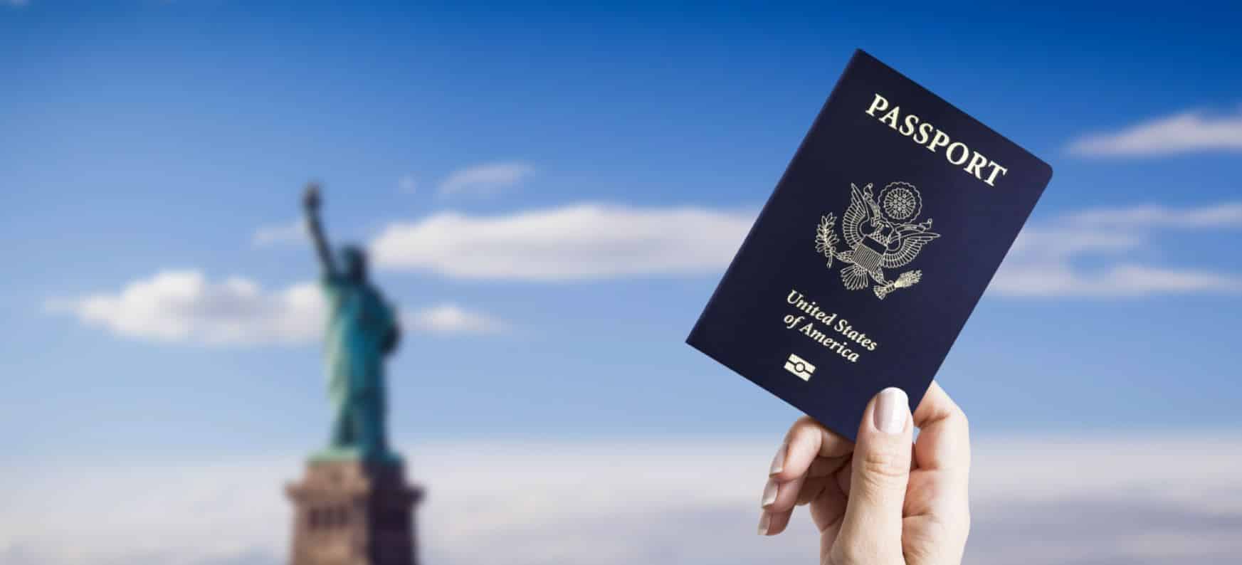 a person holding a us passport with the statue of liberty in the background