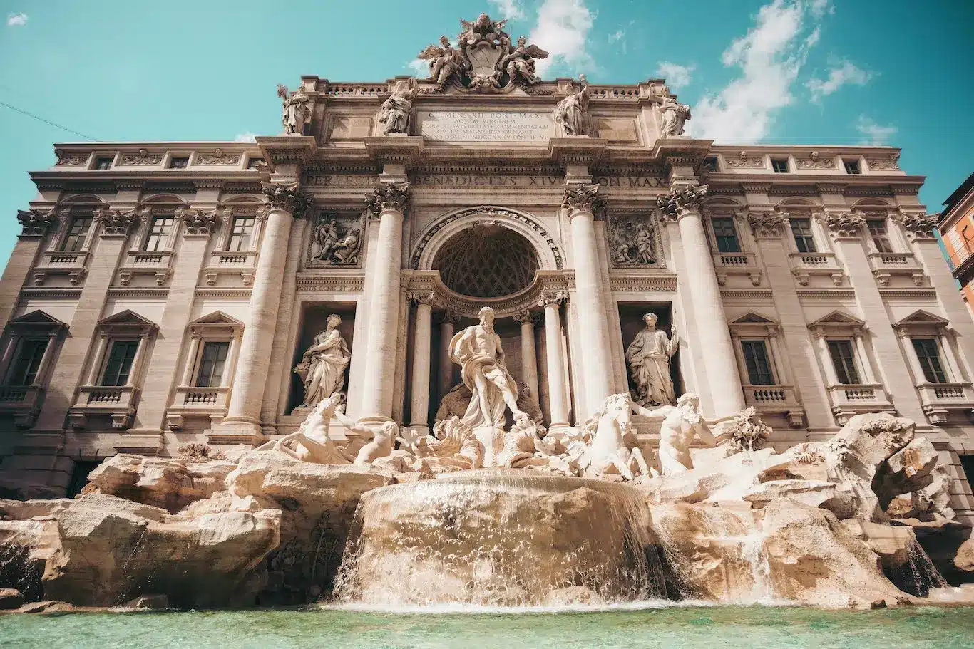 Trevi Fountain in Rome, Italy, showcasing its ornate sculptures and flowing water under a clear blue sky.
