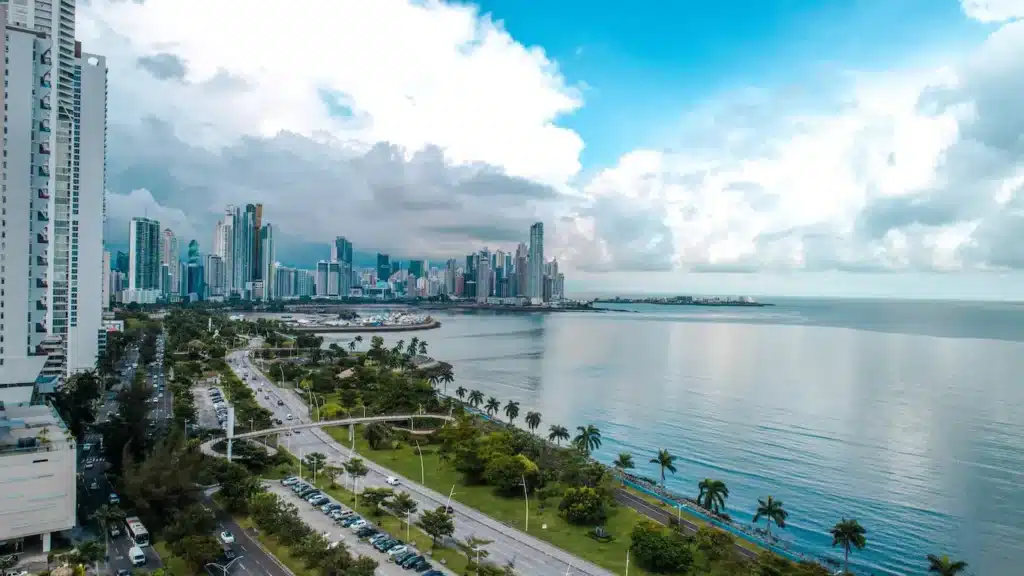 Panama City skyline featuring tall buildings, the ocean, and a road in the foreground under a clear blue sky - best countries for US citizens