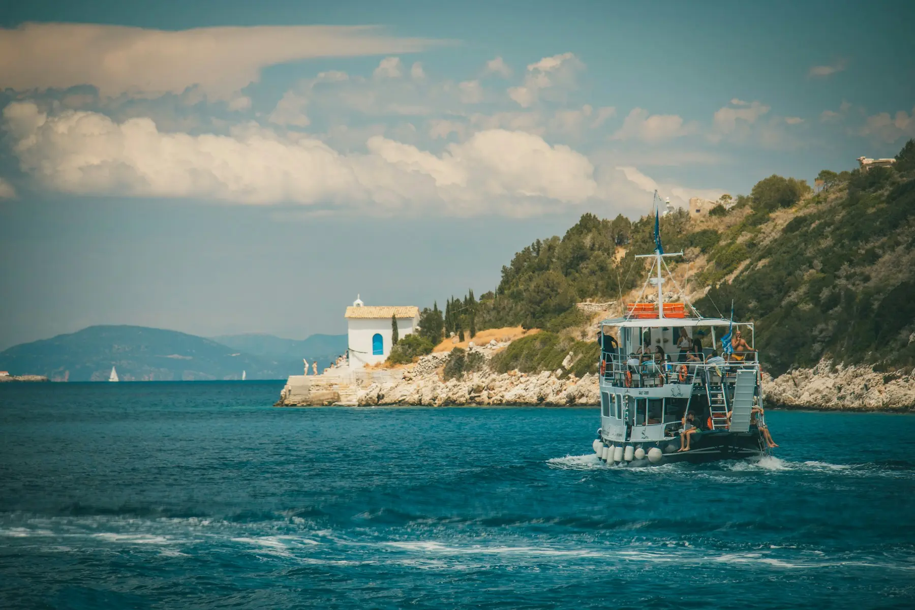 A boat glides through the water, approaching a small island surrounded by calm waves.