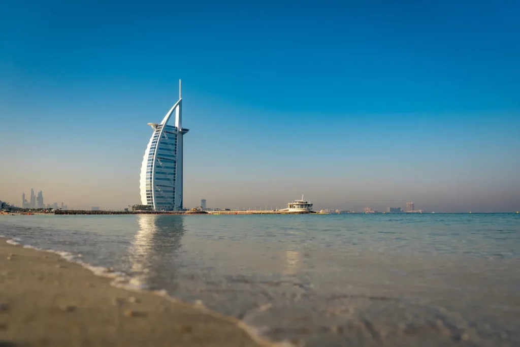 Burj Al Arab hotel in Dubai, UAE, showcasing its iconic sail-shaped architecture against a clear blue sky.