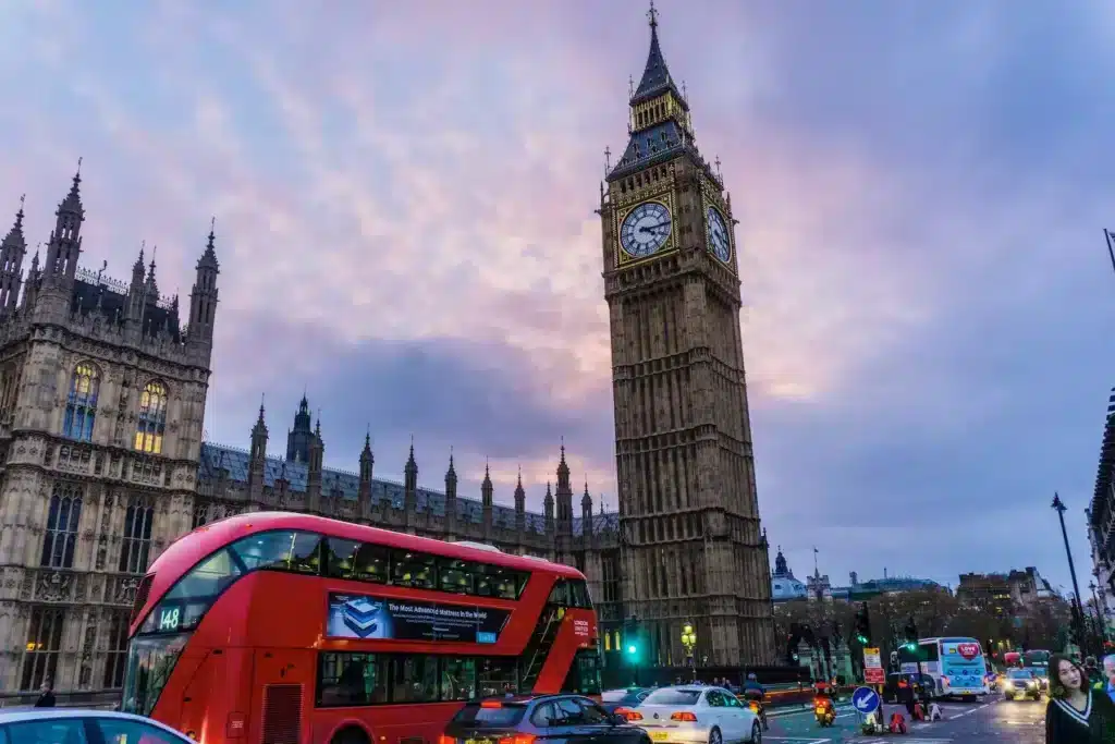 Big Ben and Westminster Bridge illuminated at dusk, with a colorful sky reflecting the evening light.